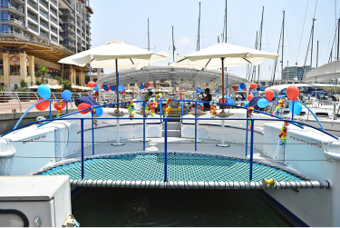 יאכטה לבנה מקושטת בבלונים בגווני כחול ואדום